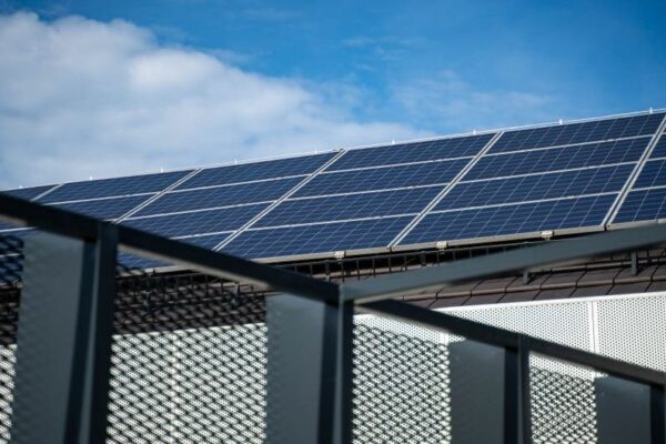 Close-up view of modern solar panels on a rooftop against a clear blue sky, representing clean energy.